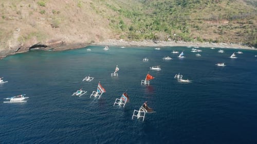 Barcos de pesca tradicionales de Jukung que regresan a la playa de Pantai Kusambi, vela con forma de garra de cangrejo, vuelo aéreo