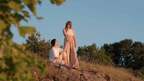 Romantic Couple Relaxing Together on Hilltop at Sunset