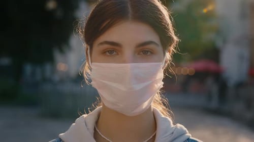 Portrait of a Beautiful Dark Haired Young Woman Wearing Protective Medical Face Mask and Standing on