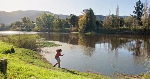 Nature, man and throwing rocks into a lake for fun, summer and activity on a vacation