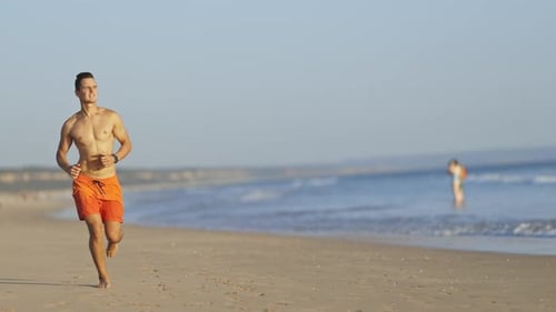 Young Athletic Lifeguard Running on the Beach