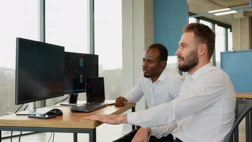 Zwei gestresste Händler schauen auf den Bildschirm und zeigen, dass die Grafik des Finanzmarkt-Charts nach unten geht