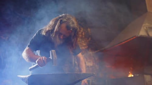 Blacksmith Forging Metal in Dark, Smoky Workshop