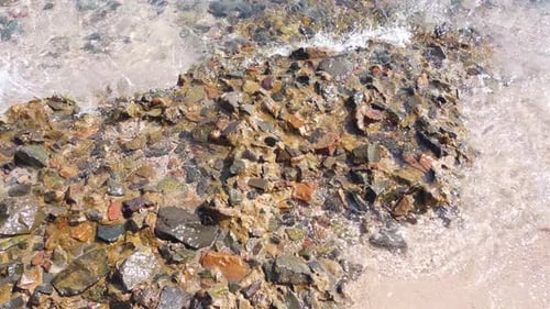 Small sea waves rush onto the shore from small pebbles. Peace from the movement of sea water or wave