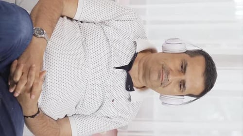 Vertical video of Unhappy man listening to music with headphones.
