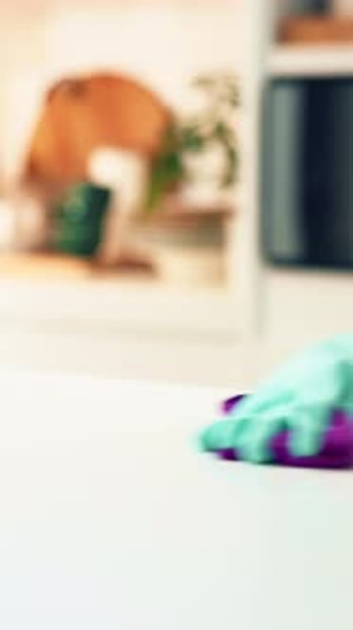 Gloved Hand Cleaning a White Surface