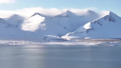 Icelandic snow-covered mountains towering over a peaceful fjord landscape