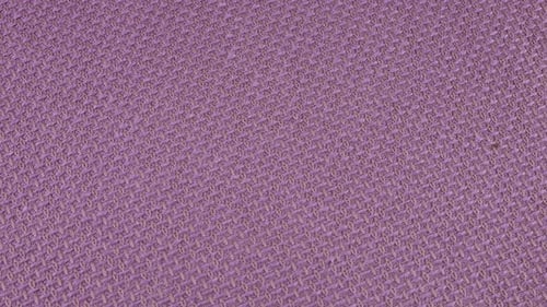 Relief, textured textile background made of purple color mauve shade cotton fabric on a rotating