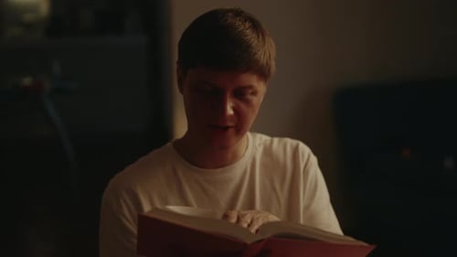 Man Reading a Book in a Dimly Lit Room