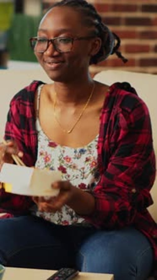 Woman Eating Noodles on Couch at Home
