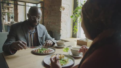 Businessman Talking with Female Colleague on Lunch in Cafe