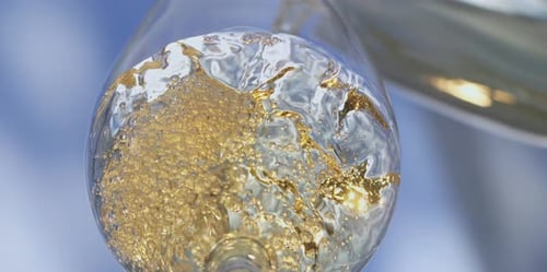Golden Liquid Poured into Glass with Bubbles