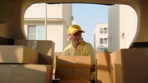 Der Zusteller entlädt Kisten mit Waren aus dem Kofferraum des Autos