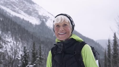 Smiling Senior Woman Hiking in Snowy Mountains