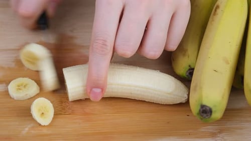 Slicing Peeled Banana on Cutting Board with Knife