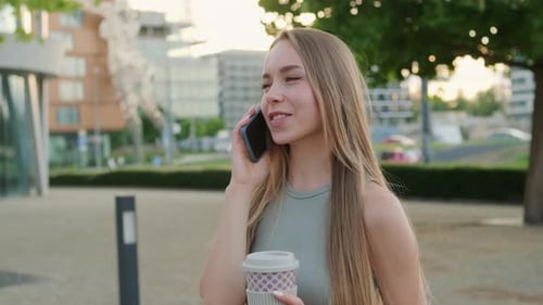 Happy Young Woman Spends Time in Park Talking on Phone