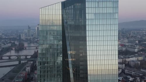 Cerrar Rodeando la torre del Banco Central Europeo del BCE que refleja el amanecer con el horizonte de Fráncfort en