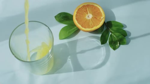 Orange Juice Pouring Into Glass With Sliced Fruit