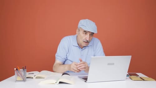 Vieil homme fermant un ordinateur portable avec une expression de colère.