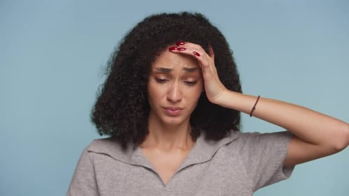 Distressed Woman Rubs Forehead in Studio Close Up