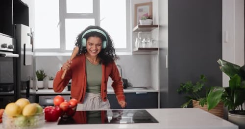 Energetic Woman Dancing in Kitchen with Headphones