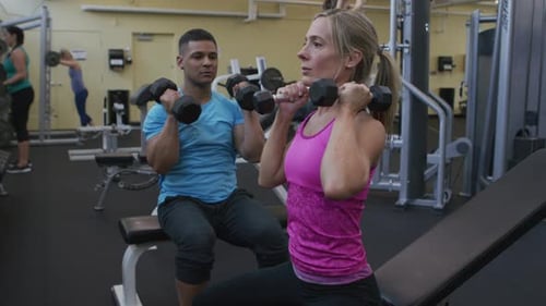 Woman Lifting Weights at Gym with Trainer