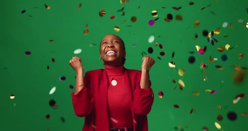 Happy, black woman and winning with confetti in studio for celebration on a green background