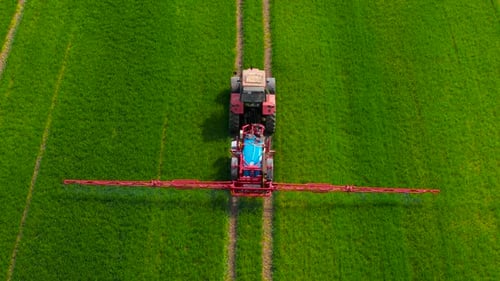 Autonomous Self Driving Tractor with Autopilot Spraying Mineral Fertilizer on Green Farmland Robotic