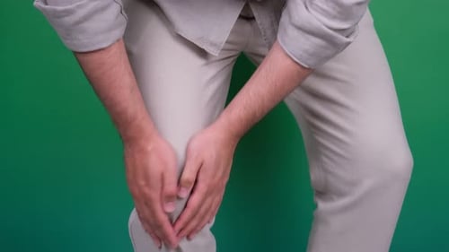 Man Holds Knee in Apparent Pain on Green Screen