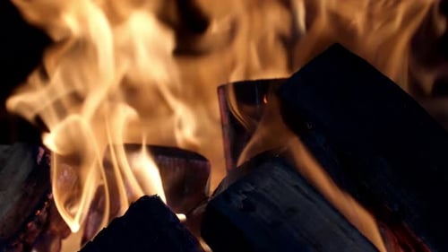 Firewood burning with a bright flame close-up in a fire at night.
