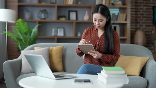 Woman Working at Home with Laptop and Notepad