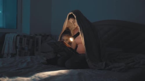Mother and Child Reading in Bed at Night