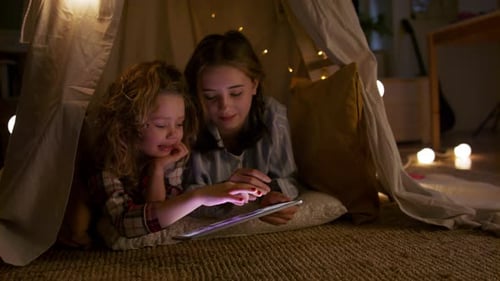 Girls Using Tablet in a Tent with Lights
