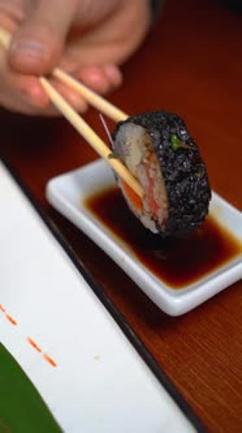 Man eats a tempura sushi roll in a restaurant