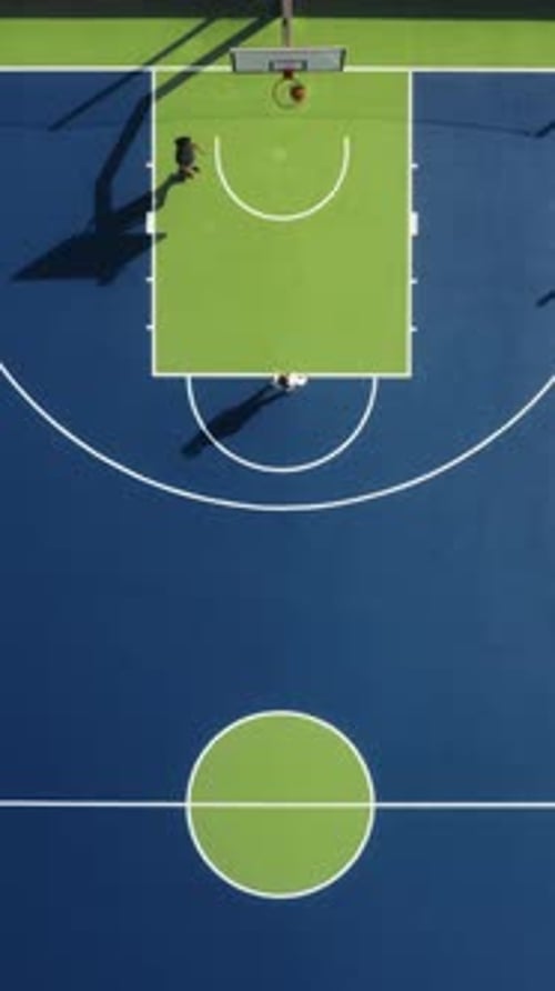 Enjoy an Aerial Perspective of Basketball Players Engaged in an Intense Game on the Court