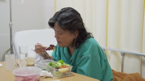 Female patient in a hospital gown enjoying her food