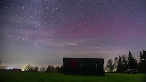 Time-lapse of the stars in the sky. milky way moving over trees in the forest with a little hut. Ni