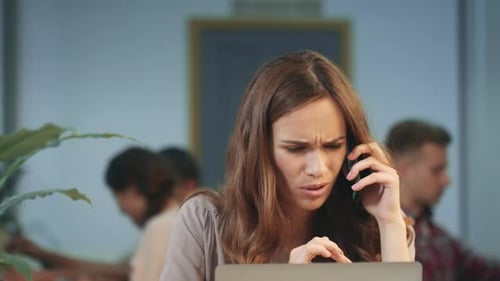 Woman Working on Laptop and Talking on Phone