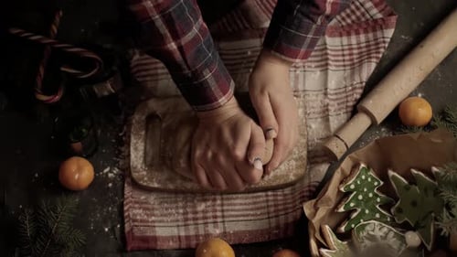 Close-up of a woman's hand making gingerbread cookies in the form of a Christmas tree and a gingerbr