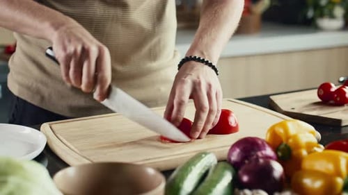 Man Cutting Red Tomato in Kitchen Preparation