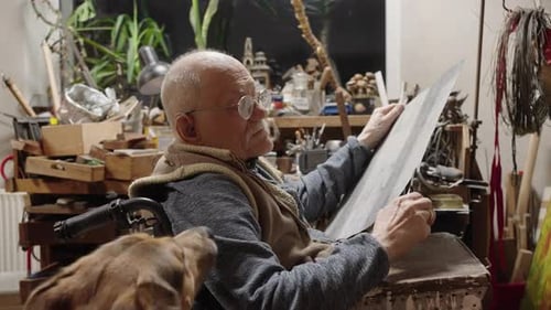 Senior Elderly Master Jeweler in Wheelchair Works in a Workshop
