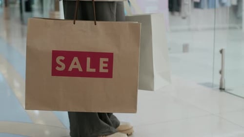 Legs of Person Holding Shopping Bag with Discounted Purchase in Mall