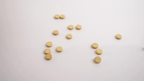 Medical Concept Pills Fall on a White Table