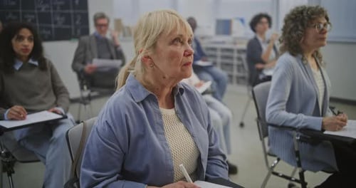 Adults Taking Notes Attending Lecture in Classroom