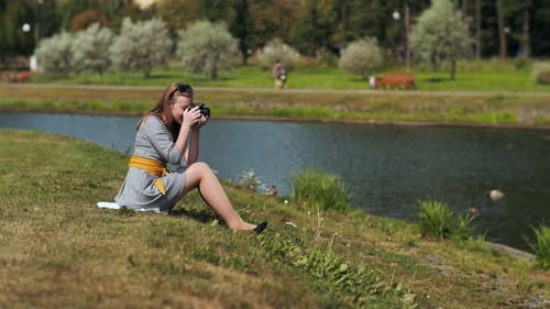 Young Woman Taking Photographs in Park by River