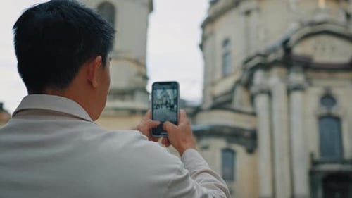 Vista trasera Hombre irreconocible turista viaja por Europa fotografiando un hito con la cámara del móvil