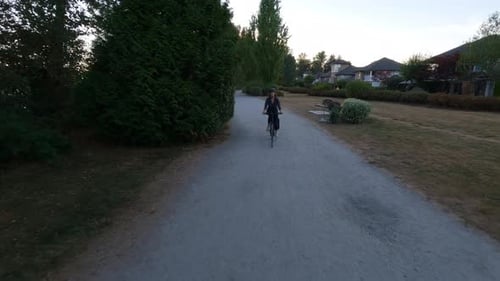 Adventure Woman Bike Riding on a Bicycle Trail Surrounded By Green Trees