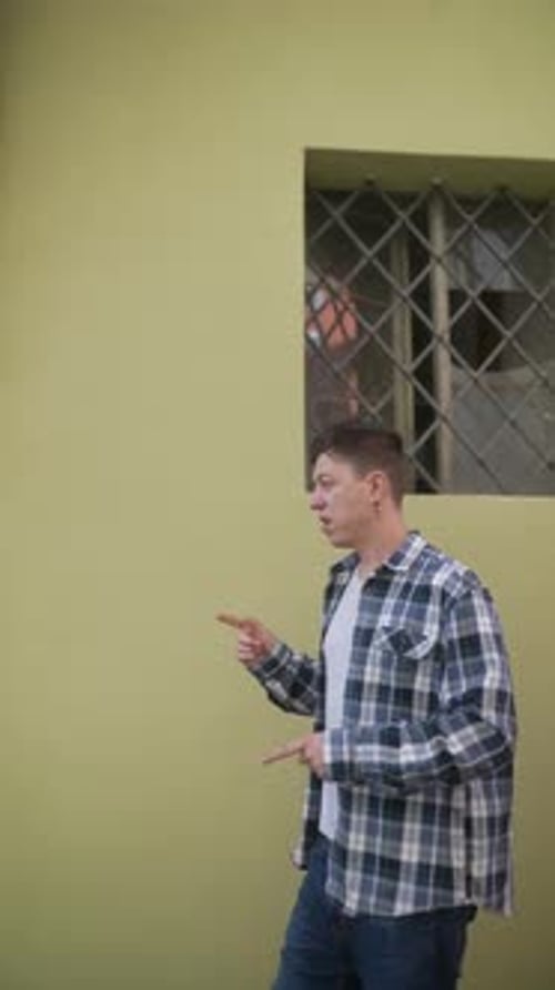 A Man in Plaid Shirt Walking By a City Window Showcasing Urban Lifestyle and Casual Fashion