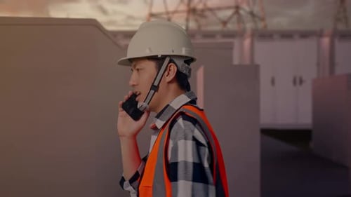 Side View of Asian Male Engineer Talking On Smartphone While Walking with Electrical Energy