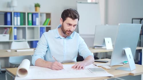 young creative designer or architect working in the office at work at a computer desk with drawings.